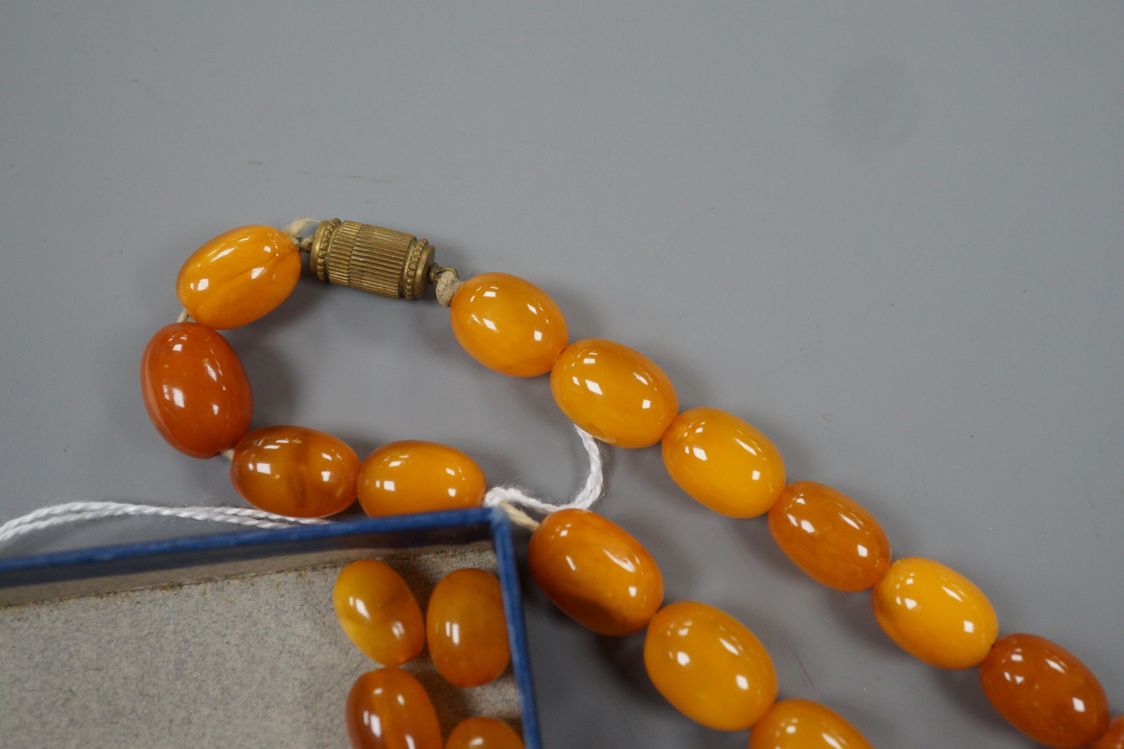 A single strand graduated oval amber bead necklace, 42cm, gross 49 grams and assorted loose amber beads, 15 grams.